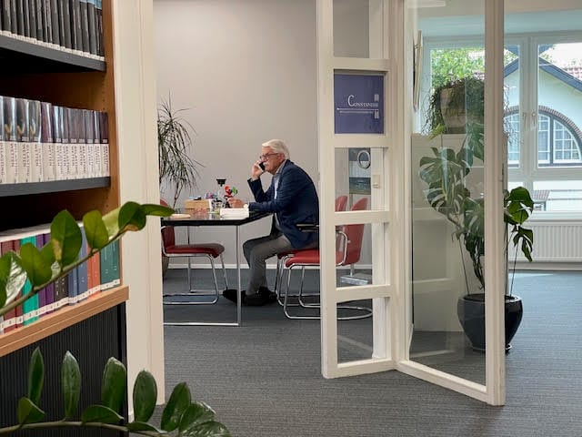 Kantoorruimte met vakliteratuur en een overlegtafel bij het raam